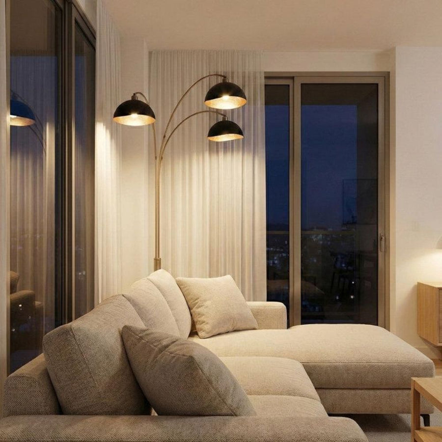 Three head arc floor lamp over beige sectional sofa at night